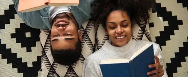 African american couple lying on the floor and reading books.